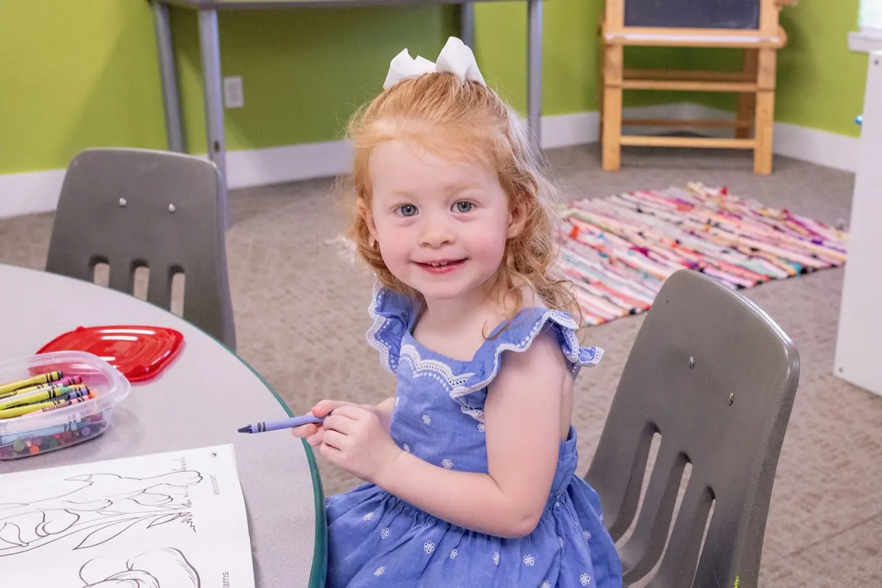 A child smiles while coloring during Haslet Bible Church child care.